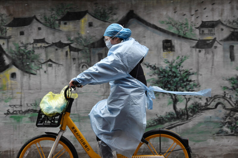 Женщина в защитном костюме едет на городском велосипеде